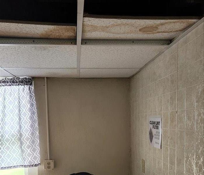 Laundry room with water stained ceiling tiles.