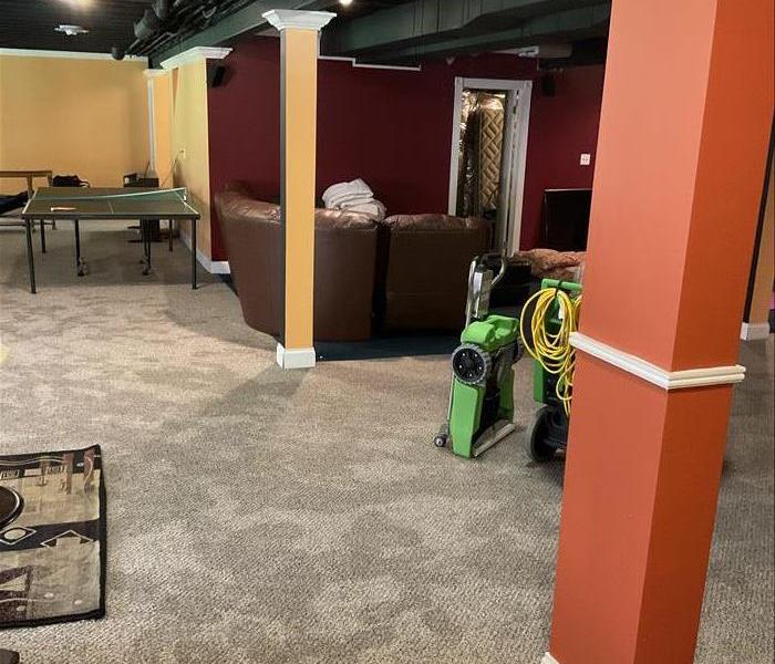 Flooded finished basement with theater and and bar. SERVPRO extractor and rover are being setup.