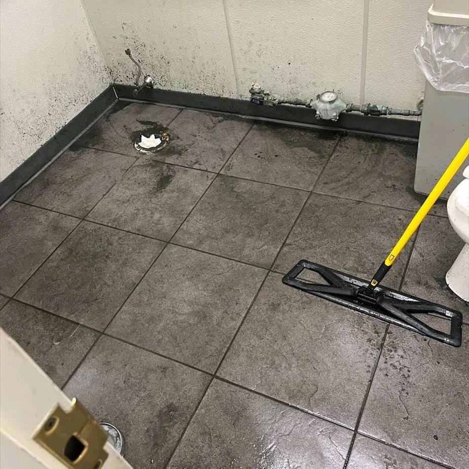 A dirty bathroom floor is shown after a sewage line backed up.