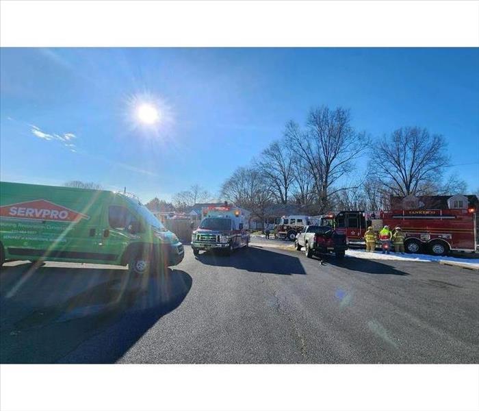 An ambulance, a SERVPRO van, and a fire truck sit in the SERVPRO parking lot